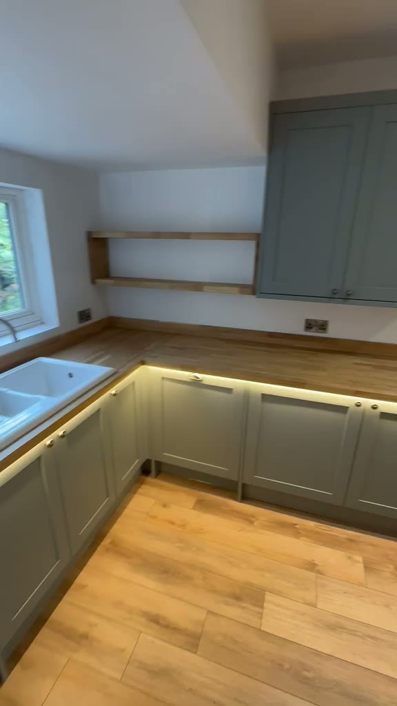 Sage green shaker kitchen with oak worktops, Belfast sink and warm LED lighting